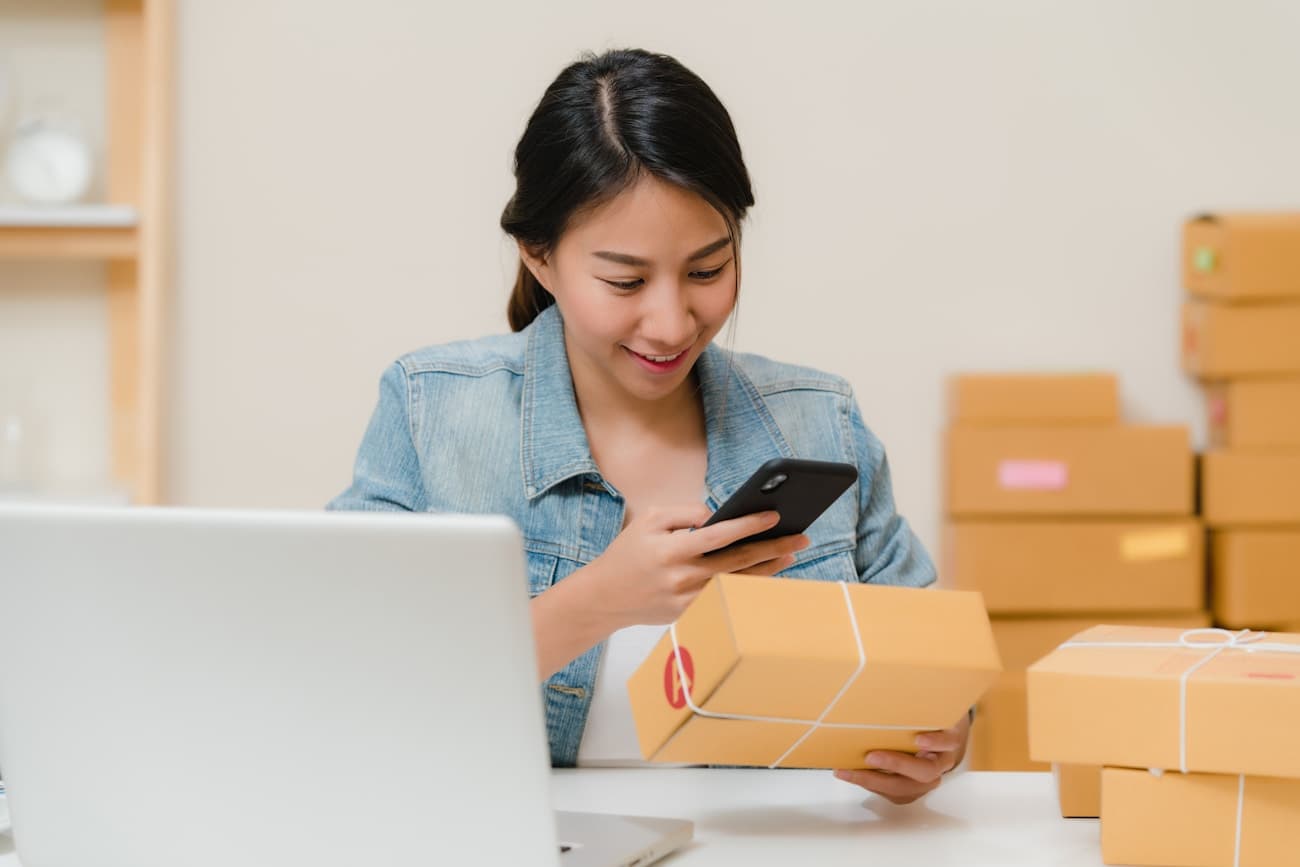 Someone checking a parcel against their laptop at a kitchen table